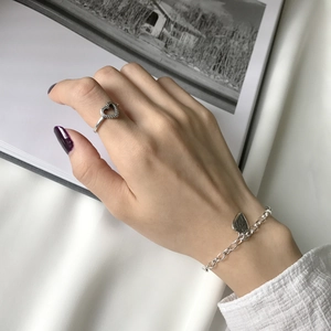 Macro detail of S925 sterling silver heart ring and matching chain bracelet set