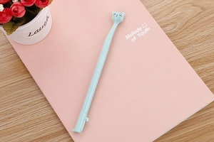 Close-up of a light blue cartoon cat gel pen on a pink notebook with floral background