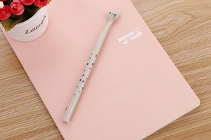 Close-up of grey cat-shaped gel pen with paw prints on a pink notebook