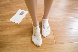 Detailed close-up of white cotton socks with cute cartoon rabbit ears and pink polka dots