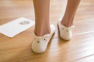 Close-up of white cotton ankle socks featuring cute 3D cartoon animal ears on wood floor