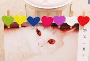 Close-up of colorful heart-shaped wooden clips for photos on postcard edges