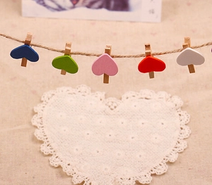 Close-up of colorful heart-shaped wooden photo clips on a hemp rope for home decor
