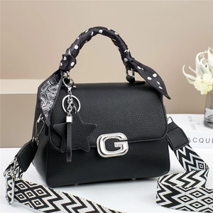 Detail van zwarte leren tas met G-logo, zijden sjaalhandvat en brede schouderriem
