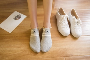 Detail of grey cartoon cat-ear ankle socks with white stripes on wooden floor