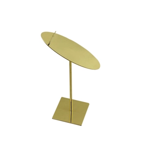 Close-up of golden metal display stand with square base and tilted platform for shoes