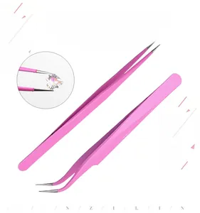 Detailed view of pink anti-static tweezers picking up small heart-shaped nail gems