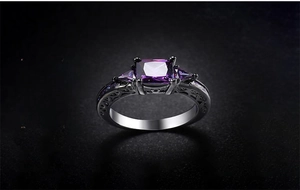 Macro shot of black gold ring featuring a purple zircon and intricate carved hollow details