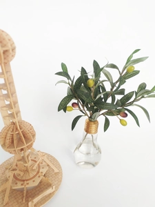 Detailed close-up of decorative artificial olive leaves next to a 3D wooden tower model