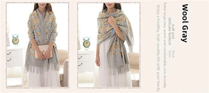 Detail of grey wool shawl featuring ethnic paisley embroidery and thick fringe edges