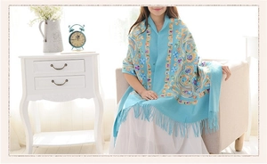 Close-up of intricate paisley floral embroidery and fringes on light blue wool shawl