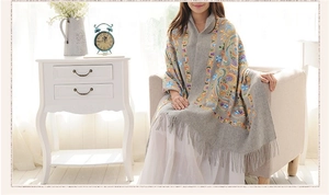 Detailed embroidery on grey wool shawl featuring colorful paisley patterns and fringes