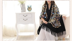Detailed embroidery of colorful paisley patterns and tassels on a black wool shawl