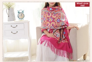 Detail of rose red wool shawl with traditional paisley embroidery and delicate fringes