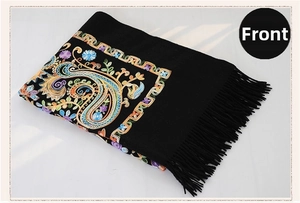 Detail of colorful Paisley embroidery on black wool shawl with fringe edges