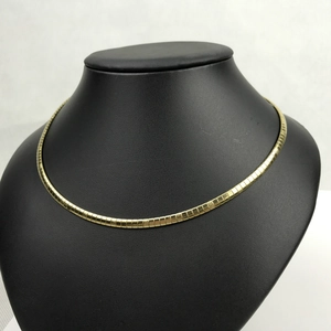 Close-up of a minimalist golden stainless steel omega chain necklace on a black bust