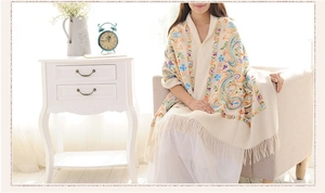 Detailed embroidery of paisley patterns on a beige wool shawl with elegant tassels
