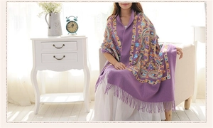 Detailed embroidery and fringe edges on a purple wool shawl worn in a cozy home setting