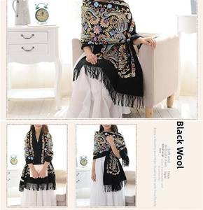 Detail of black wool shawl with colorful paisley floral embroidery and long fringes