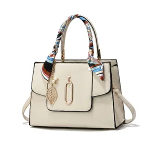 Detail of elegant handbag texture with colorful scarf handles and metal ring accents