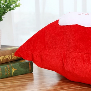 Red plush Christmas pillow with white fluffy applique on a wooden table setup