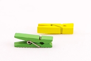 Close-up of green and yellow wooden clips with metal springs for photo decoration