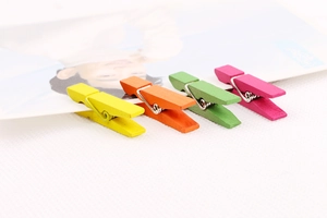 Close-up of four colorful wooden photo clips in yellow orange green and pink tones