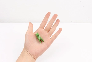 Detailed view of a small green wooden photo clip held in hand showing 3.5cm scale