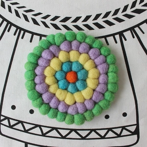 Close-up of colorful handmade wool felt ball coaster with concentric circle pattern