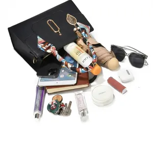 Detail showing the large capacity of a black faux leather tote bag with silk scarf and charms