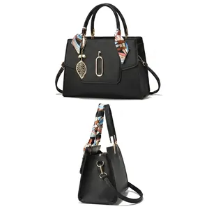 Detail of black cross-grain leather tote with gold leaf pendant and silk scarf handle
