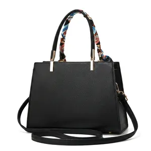 Detail view of black pebble leather handbag with gold hardware and floral scarf handle