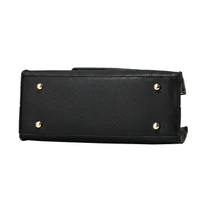 Macro detail of black lychee texture leather handbag base with four gold metal protective feet