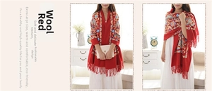 Detail of red wool shawl featuring ethnic paisley embroidery and elegant fringe edges