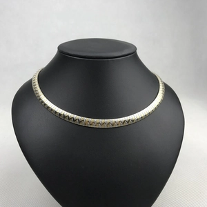 Detail of 4/6mm wave-sand bicolor V-shaped stainless steel choker on black stand