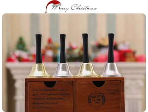 Christmas hand bells in gold and silver with black handles and a rustic wooden box