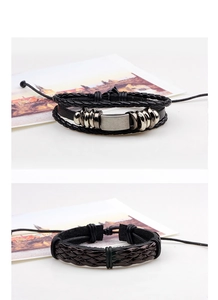 Detail of multi-layer black braided leather bracelet with metal plate and adjustable knot
