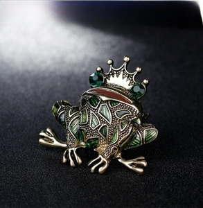 Macro shot of crown frog brooch with green enamel pattern and emerald crystal eyes