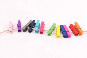Close-up of colorful mini wooden clips for photo display hanging on jute rope