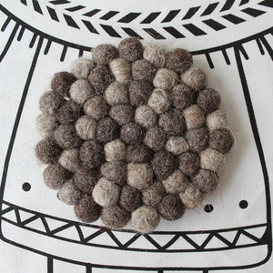 Macro shot of handmade round wool felt ball coaster in dark brown and beige tones