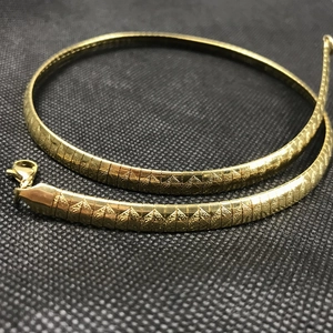 Gold flat snake chain necklace with wave texture and lobster clasp on black background