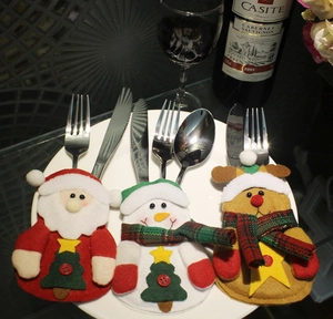 Detailed view of Santa, Snowman and Reindeer felt cutlery holders on a white dinner plate