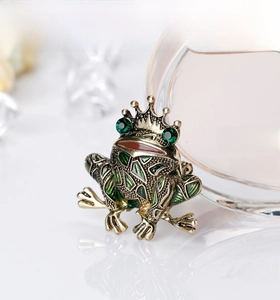 Detailed macro of vintage gold frog king brooch with green enamel and emerald rhinestones