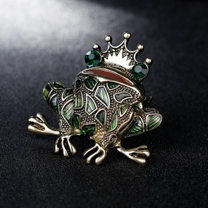 Retro frog king brooch with crown and green enamel on a black matte background