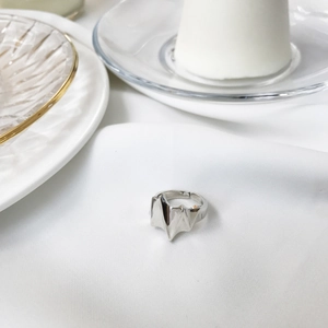 Polished silver geometric bat-wing ring displayed on elegant white silk background