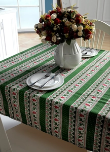 Close-up of green Christmas tablecloth with red reindeer and tree patterns and tableware