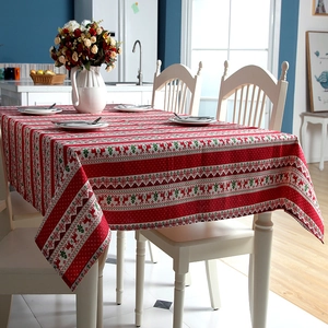 Close-up of festive red Christmas tablecloth featuring reindeer and trees on table