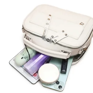 Dettaglio dell'interno capiente della borsa a tracolla bianco crema con oggetti quotidiani