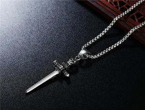 Detail view of silver punk skull and sword pendant on dark textured surface