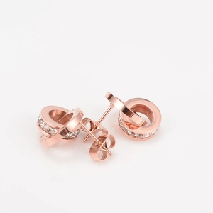 Close-up of rose gold interlocking earrings with Roman numerals and sparkling cubic zirconia